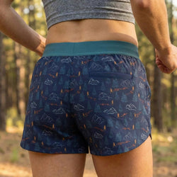 Person wearing blue patterned running shorts with a forest background