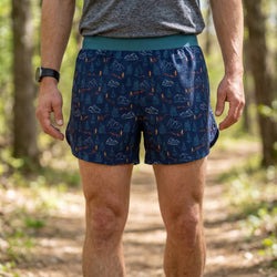 Person wearing blue patterned shorts in a forest setting