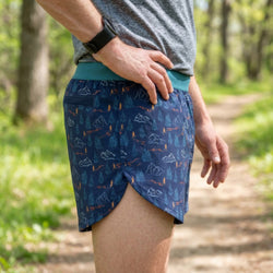Person wearing blue patterned shorts in a forest setting