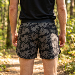 Person wearing black and gray patterned shorts in a forest setting