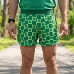 Person wearing green checkered shorts with shamrock pattern outdoors