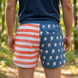Person wearing a pair of running shorts with American flag design outdoors.