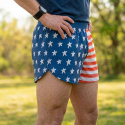 Person wearing blue shorts with white star pattern and red, white, and blue striped shorts outdoors.