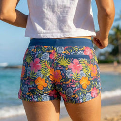 Person wearing colorful floral shorts on a beach