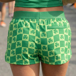 Green checkered shorts with shamrock pattern worn by a person.