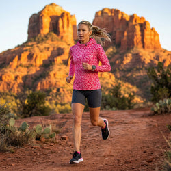 woman running in a pink lightweight running hoodie ourdoors at a canyon