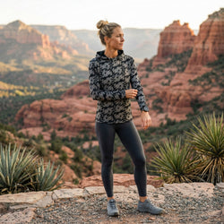 Woman running in a canyon wearing a jackalope patterned running hoodie
