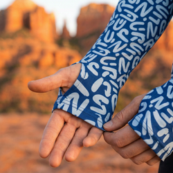 Close-up of hands wearing blue patterned sleeves against a blurred natural background showing a thumbhole