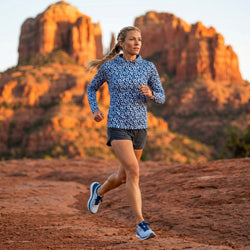 Woman wearing a blue running hoodie jogging in a canyon