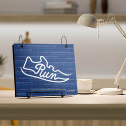 Blue bibfolio with white shoe design and 'Run' text on a desk.