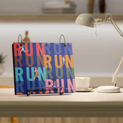 Colorful bibfolio with 'RUN' text on a desk next to a lamp and cup.