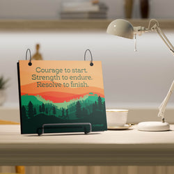 Desk with motivational bibfolio, lamp, and cup in a home office setting