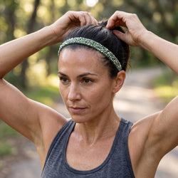Woman adjusting her hair with a green headband outdoors