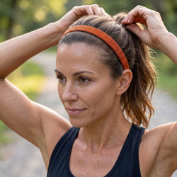 Woman adjusting her hair with an orange headband outdoors