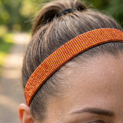 Close-up of a person wearing an orange headband with a blurred natural background