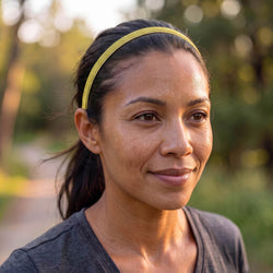 Woman wearing a yellow headband outdoors with a blurred natural background