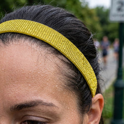 Close-up of a person wearing a yellow headband with a blurred outdoor background