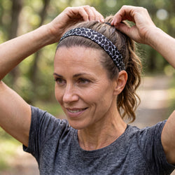 Woman adjusting a headband outdoors with a blurred natural background