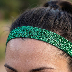 Close-up of a person wearing a green glittery headband outdoors.