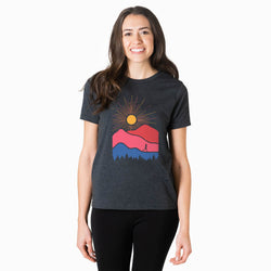 Woman wearing a t-shirt with a graphic design of a sun and mountains on a white background