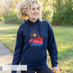 Woman wearing a navy hoodie with a mountain graphic design outdoors