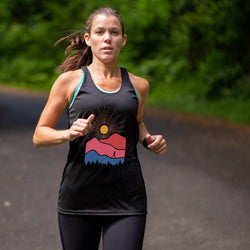 Woman running outdoors on a path with greenery in the background