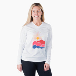 Woman wearing a white long-sleeve shirt with a colorful mountain design on a white background