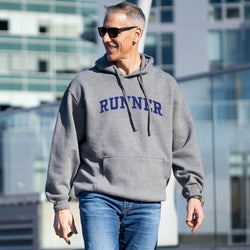 Man wearing a gray hoodie with 'RUNNER' printed on it, walking outdoors.