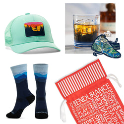 Image of a trail runner gift set that includes a teal trucker hat, socks, a cocktail glass & sticker with a red gift bag.