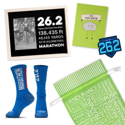 Collection of marathon-themed items including socks, a photo frame, a sticker, and a greeting card on a white background. Includes a green gift back with motivational words for runners.