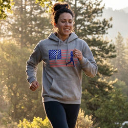 Woman running outdoors wearing a hoodie with an American flag and running figure design.
