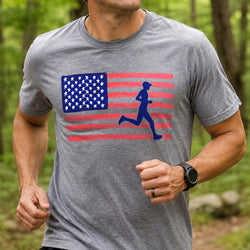 A man running outdoors wearing a heather gray t-shirt with a graphic of a red and white American flag and a blue silhouette of a running person.