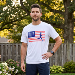 Man wearing a white t-shirt with an American flag and running figure design, standing outdoors.