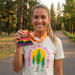 Woman runner holding a medal and a 'happy hour' sign in a forest trail setting