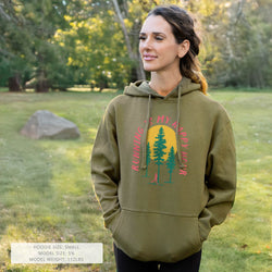 Woman wearing a green hoodie with nature-themed happy hour design in a park setting