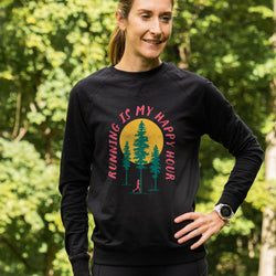 Woman wearing a black sweatshirt with a nature-themed happy hour design in a forest setting