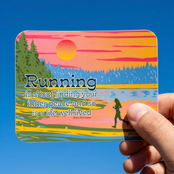 Colorful sticker with a scenic design and running quote held by a hand against a blue sky.