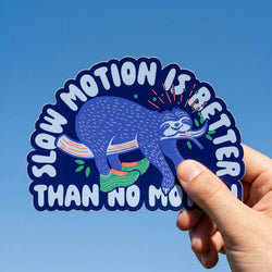 Sticker with a sloth design and text 'Slow motion is better than no motion' held against a blue sky.