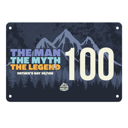 Running race bib with mountain and forest design, text 'The Man The Myth The Legend' and number 100 on a blue background.