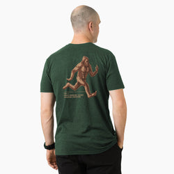 Man wearing a green t-shirt with a Sasquatch graphic on the back, standing against a white background.