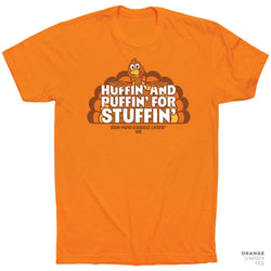 An orange short-sleeve t-shirt with a cartoon turkey graphic and the text 'HUFFIN' AND PUFFIN' FOR STUFFIN'' on the front, displayed on a clean white background.
