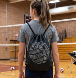 Person wearing a volleyball drawstring bag with text in an indoor sports facility