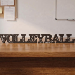 Decorative word sculpture spelling 'VOLLEYBALL' on a wooden surface.