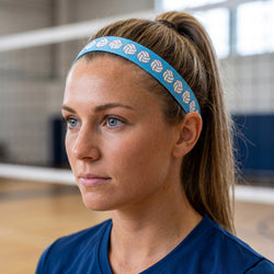 Woman wearing a blue headband with a volleyball pattern, looking to the side in an indoor setting.