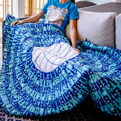 Person sitting on a couch with a blue and green patterned volleyball blanket