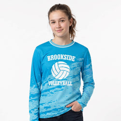 Girl wearing a blue 'Brookside Volleyball' long-sleeve shirt on a white background