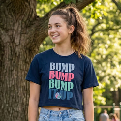 Young woman wearing a navy blue t-shirt with colorful 'BUMP' text in an outdoor setting