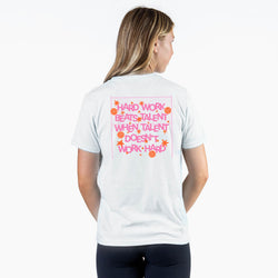 A woman shown from the back wearing a white t-shirt with a pink graphic text design that reads 'HARD WORK BEATS TALENT WHEN TALENT DOESN'T WORK HARD' with small orange stars.