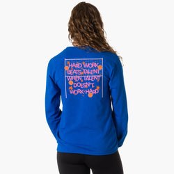 A woman viewed from behind wearing a bright blue long-sleeve sweatshirt with a volleyball-themed graphic on the back. The graphic features the text 'HARD WORK BEATS TALENT WHEN TALENT DOESN'T WORK HARD' in pink and orange lettering with orange volleyballs and white net lines.