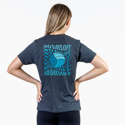 A woman viewed from the back wearing a dark heather gray t-shirt with a blue volleyball graphic and the text 'NO DAYS OFF' repeated in blue. She is standing with her hands on her hips against a clean white background.